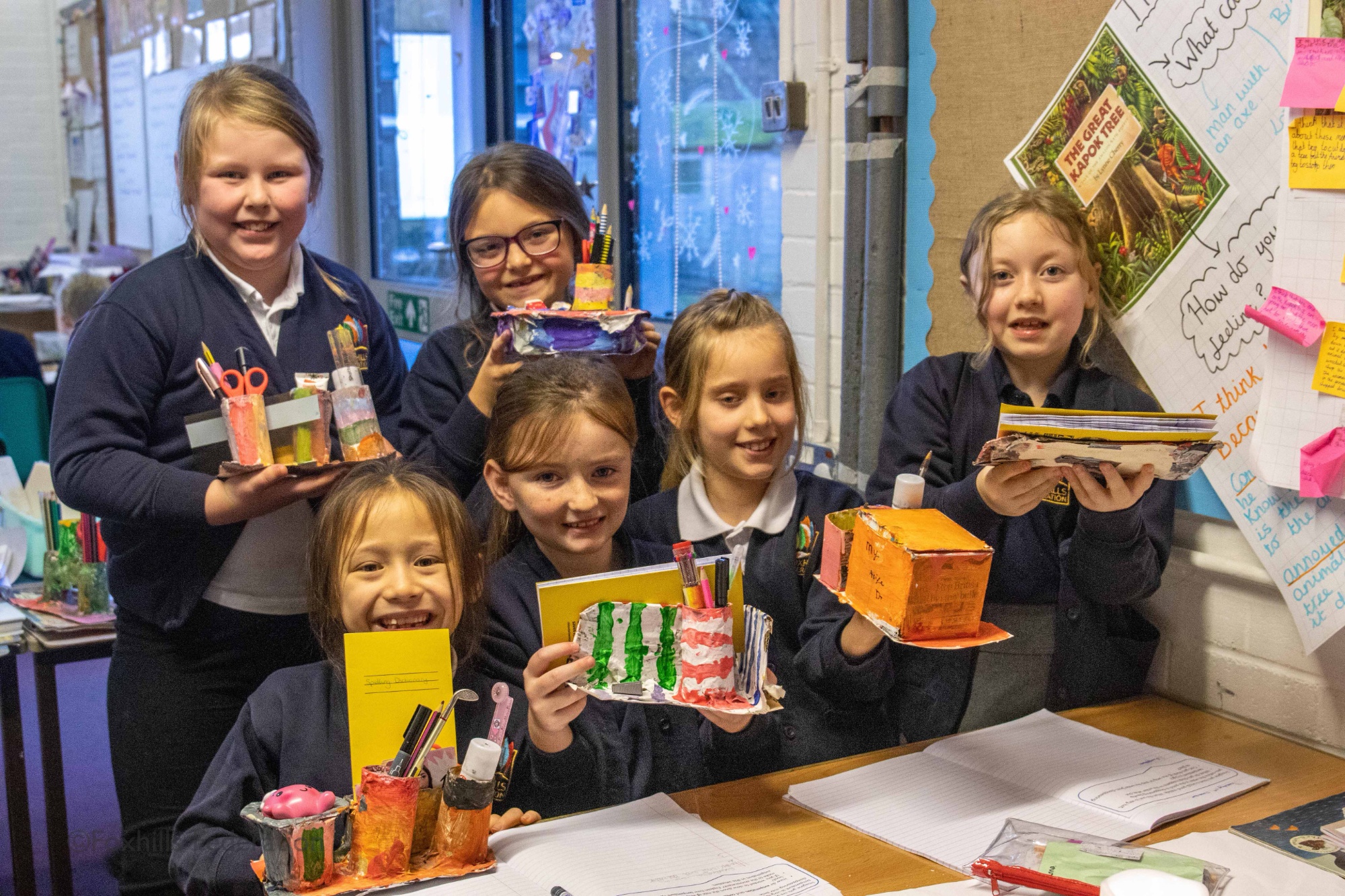 Girls smile and hold homemade desk tidies.