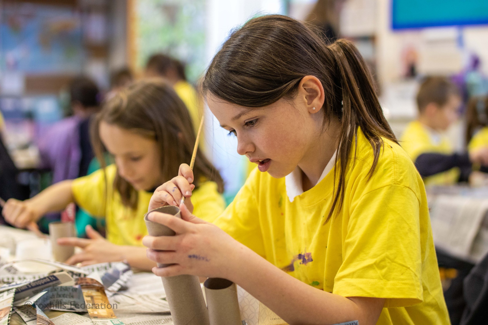 Children make homemade desk tidies.