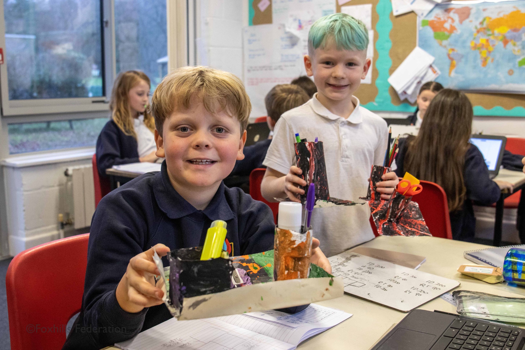 Boys smile and hold homemade desk tidies.