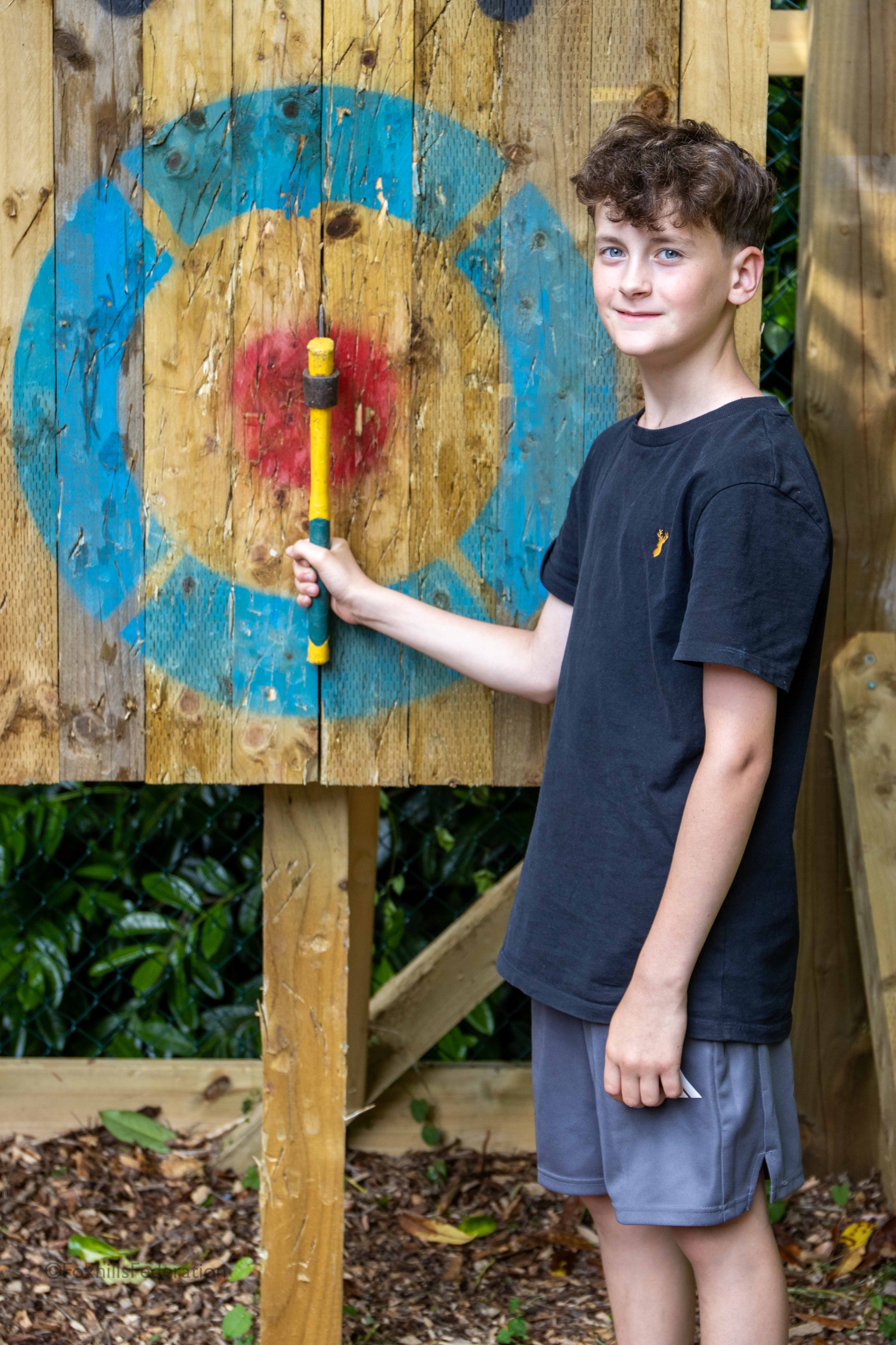 A boy poses with a axe he has just thrown