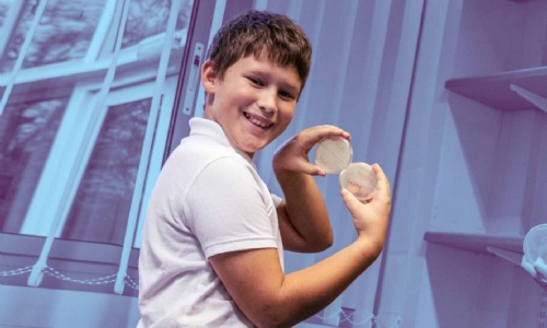 A Spotlight on Foxhills reporter hold two petri dishes.