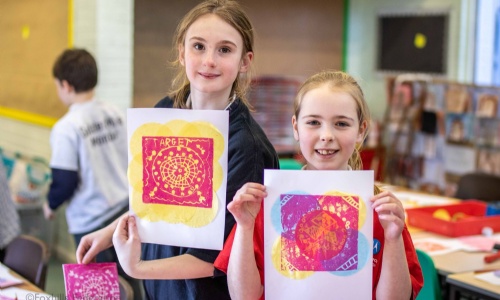 Children hold up work created by stamp printing.