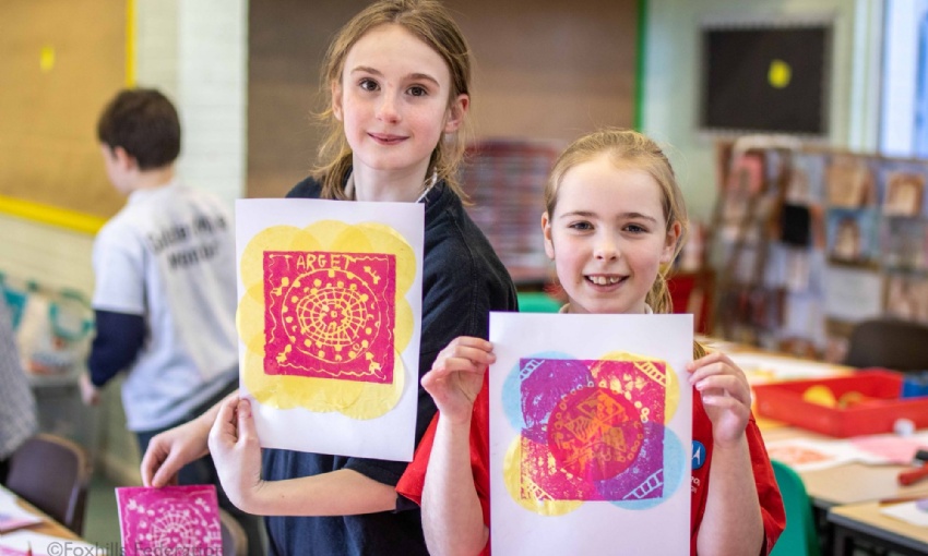 Children hold up work created by stamp printing.